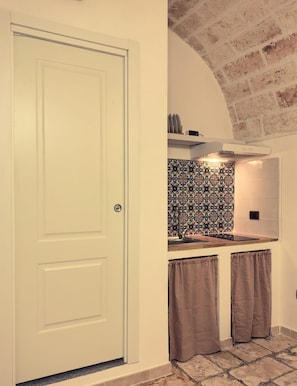 A kitchen with a white door, patterned backsplash, and a brick wall. - Dimora Pietre Gemelle, Modugno, Bari (Modugno)