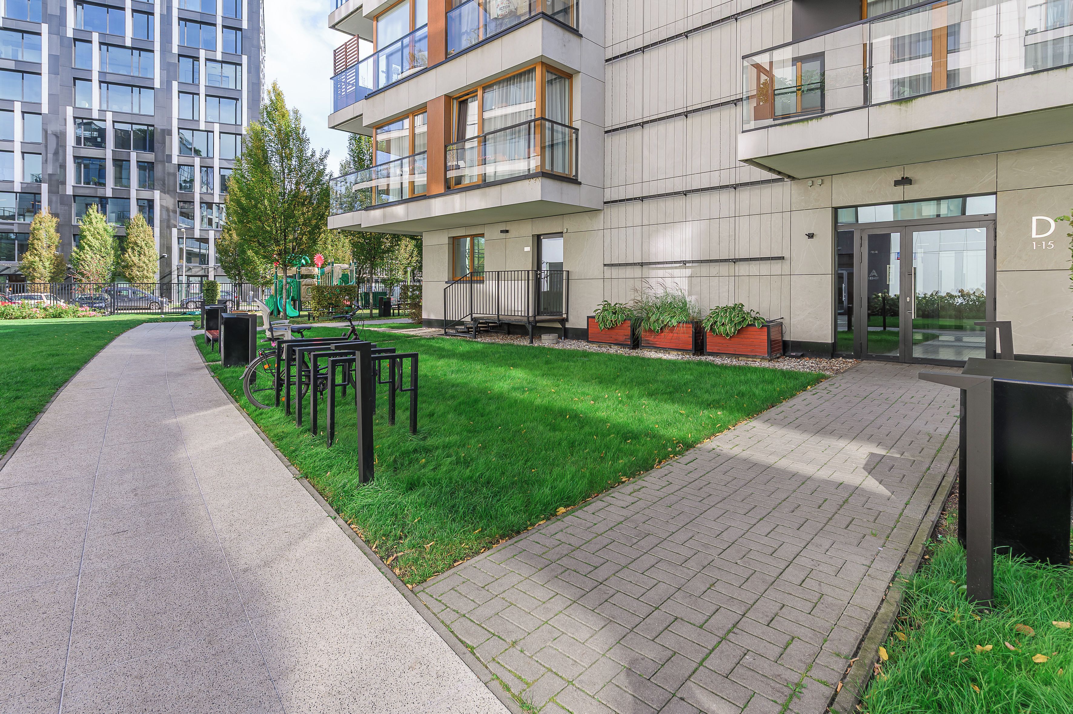 A modern building with a paved walkway, outdoor seating, and a playground.