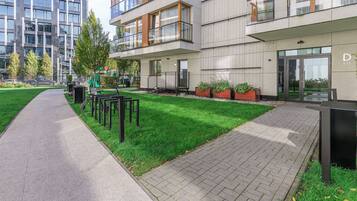 A modern building with a paved walkway, outdoor seating, and a playground.