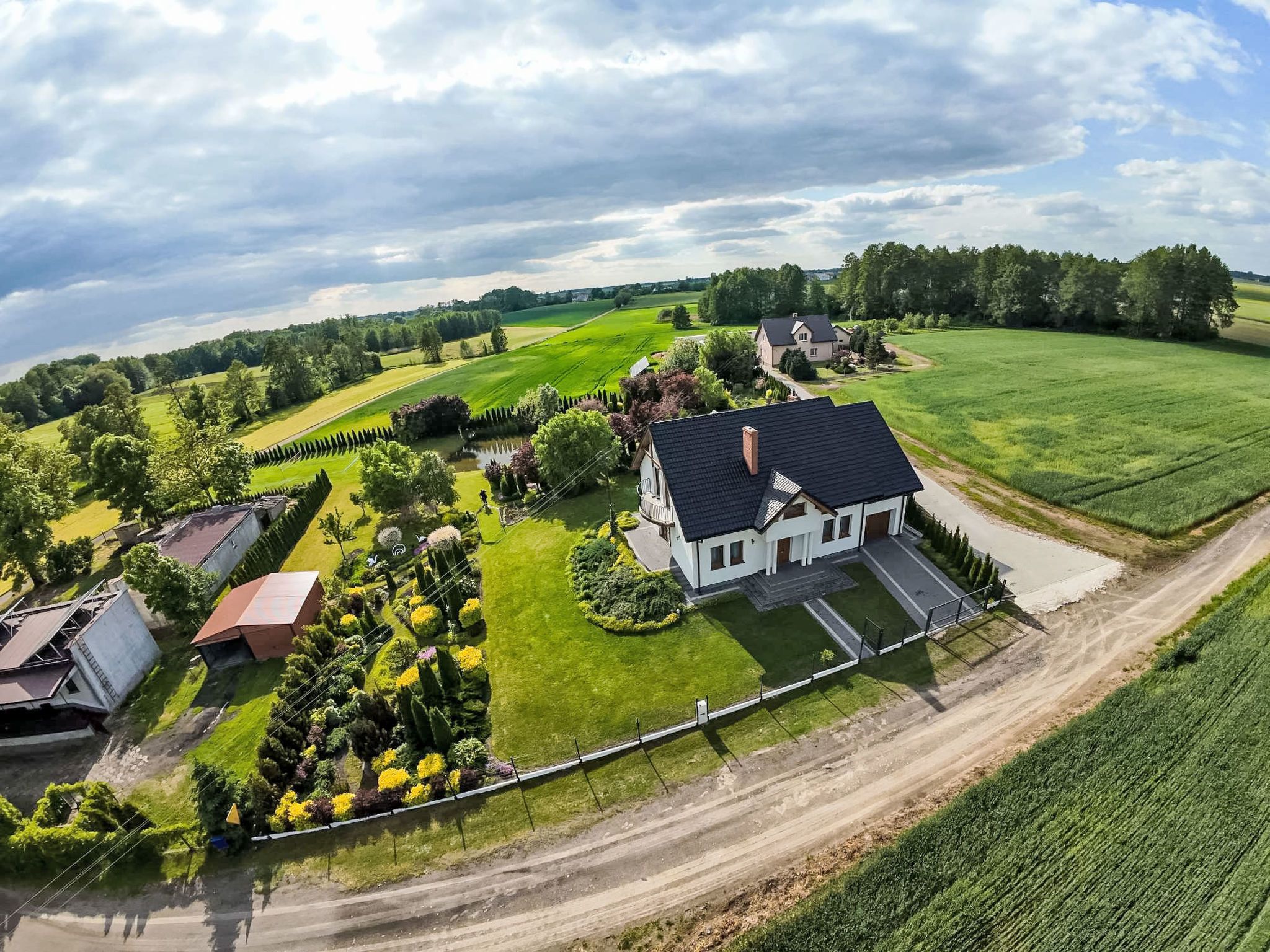 Ein großes Haus mit gepflegtem Rasen und Garten, umgeben von Feldern und Bäumen.