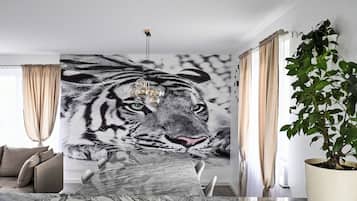 A modern living room with a large tiger mural, a marble coffee table, a sofa, and a potted plant.