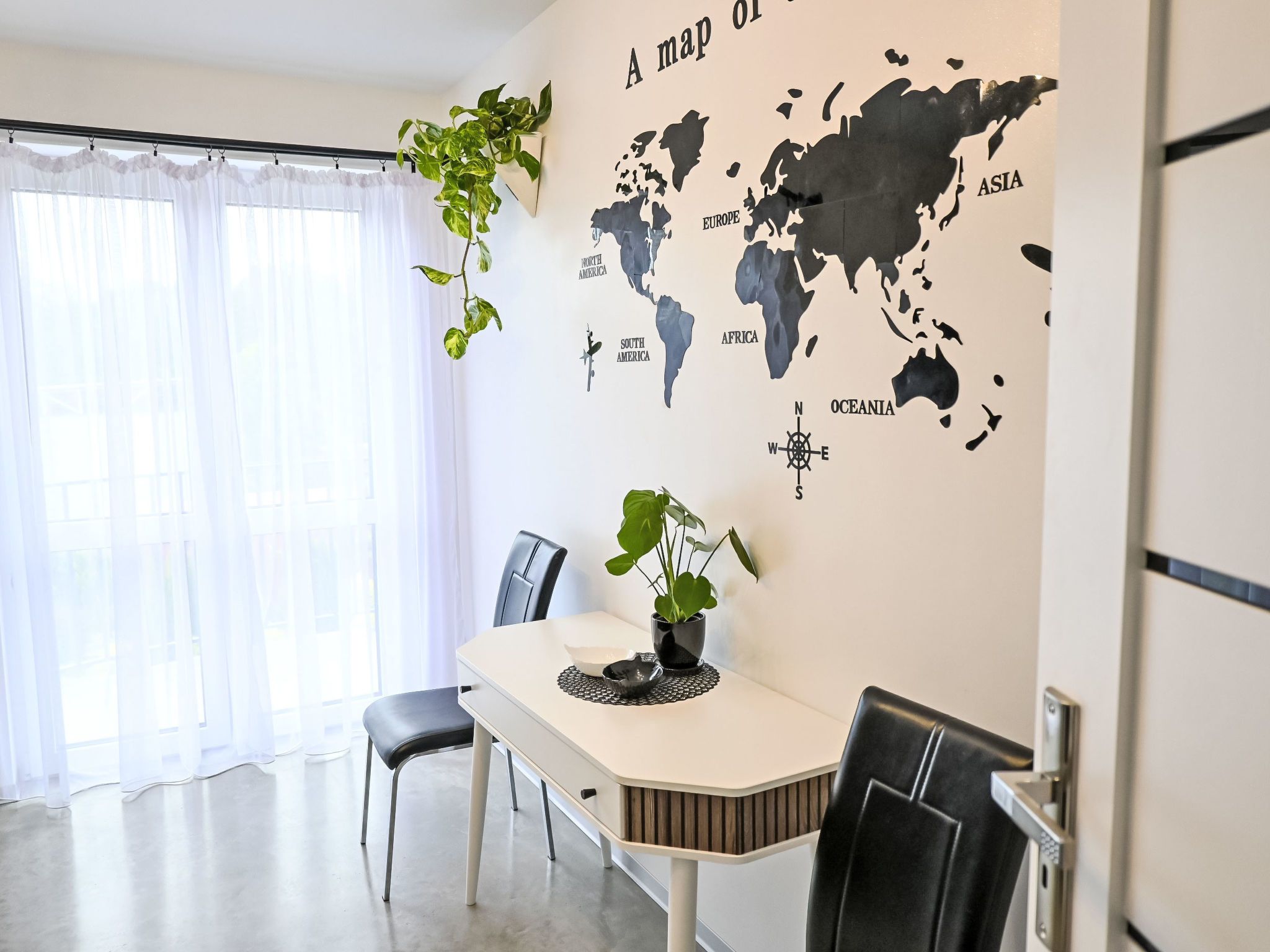 Comedor con un mural de un mapa mundial, una mesa, sillas y plantas en macetas.