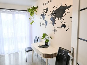 Un espace repas agrémenté d’un mur décoré d’une carte du monde, d’une table, de chaises et de plantes en pot.