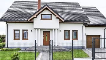 Une maison à deux étages, avec un toit recouvert de tuiles, une porte d’entrée et un petit porche.