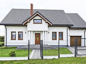 A two-story house with a tiled roof, a front door, and a small porch.