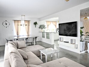 A modern living room with a sofa, coffee table, and a TV on a white stand.