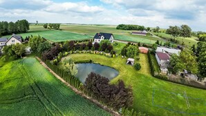 Un paysage rural avec un étang, des maisons et des champs à perte de vue.