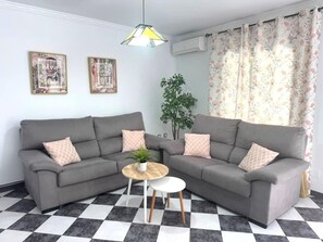 Ein Wohnzimmer mit zwei grauen Sofas, einem kleinen runden Tisch und einem Blumentopf.