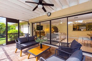 Un salon moderne comprenant un canapé, des fauteuils, une table basse et un ventilateur de plafond.