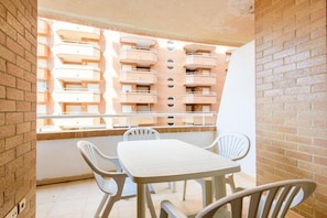 A balcony with a white table and chairs, overlooking a building with multiple balconies. - Oropesa Apartment with Terrace (Orpesa)