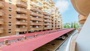 Un hotel de diverses plantes amb balcons i una zona de pàrquing coberta.