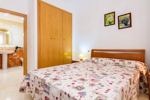 A bedroom with a bed, a wooden wardrobe, a bathroom with a mirror, and two framed pictures on the wall. - Oropesa Apartment with Terrace (Orpesa)