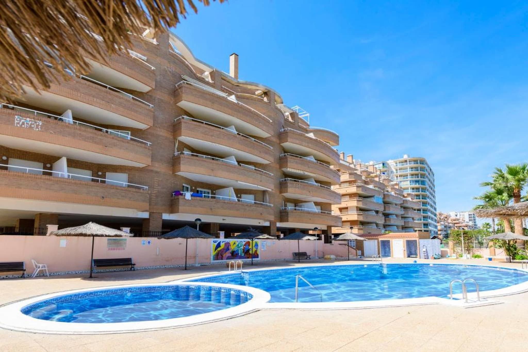A hotel with multiple balconies, a swimming pool, and a mural.