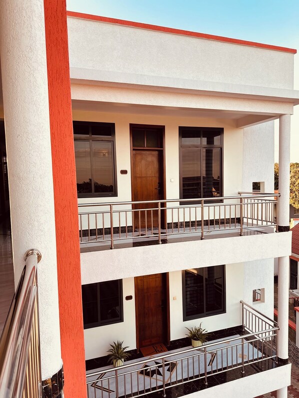 A multi-story building with a balcony, a wooden door, and a number '304' sign.