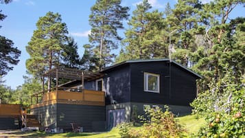 Une cabane dotée d’une terrasse, entourée d’arbres.