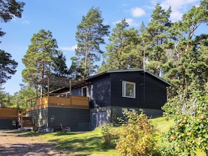 Eine Hütte mit einer Terrasse, umgeben von Bäumen.