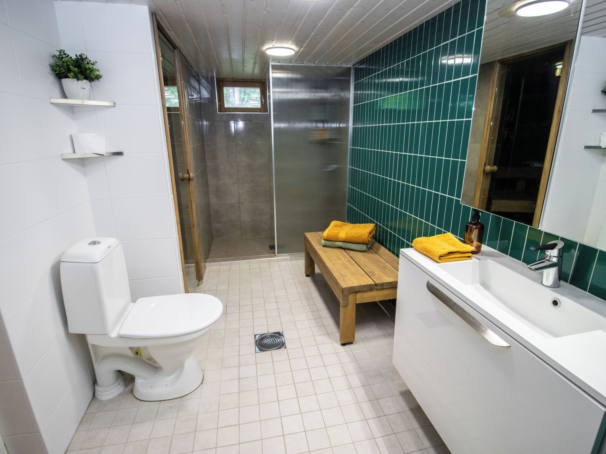 Une salle de bain avec des toilettes, un lavabo et un banc.