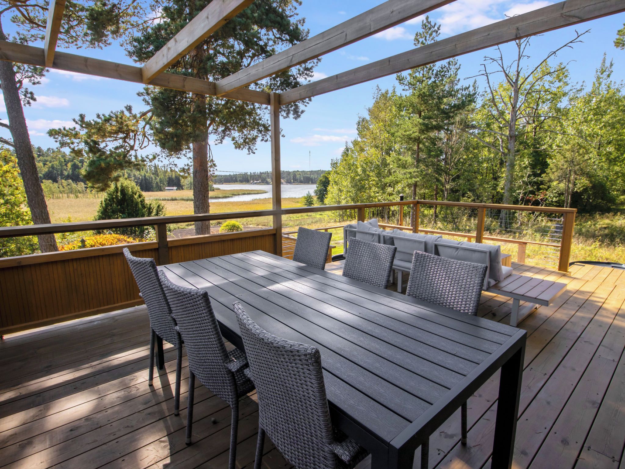 Une terrasse en bois avec une table et des chaises, offrant une vue sur un paysage naturel.