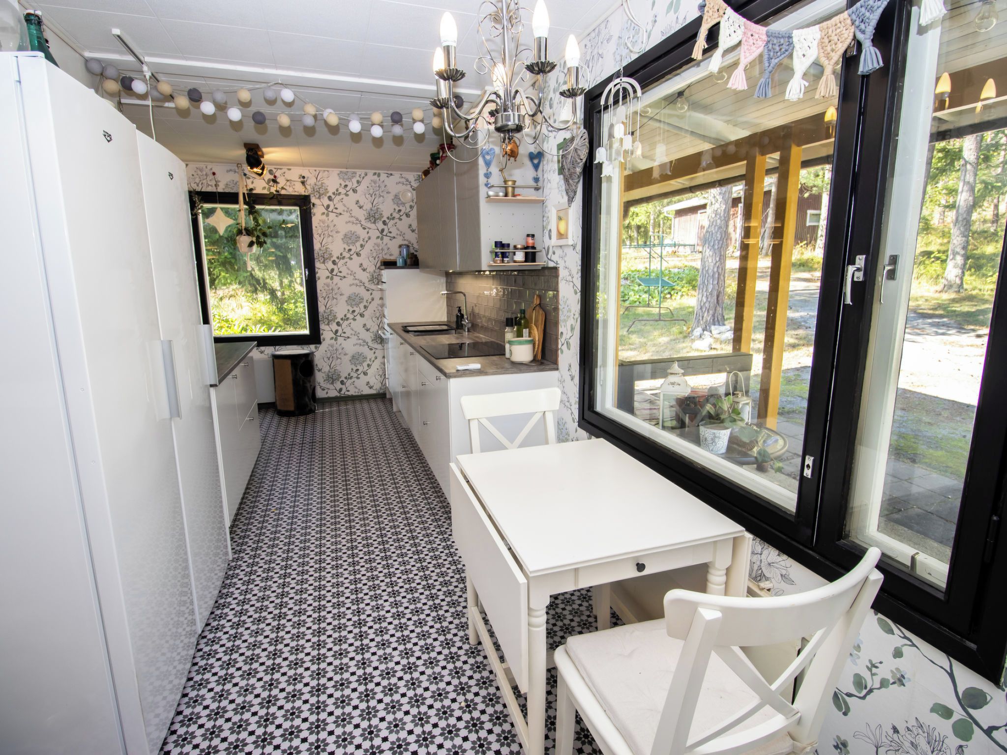 A compact kitchen with a dining area, a window with a view, and a chandelier.