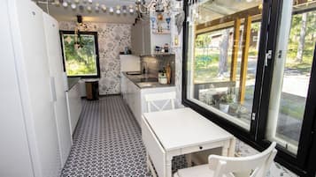 A compact kitchen with a dining area, a window with a view, and a chandelier.
