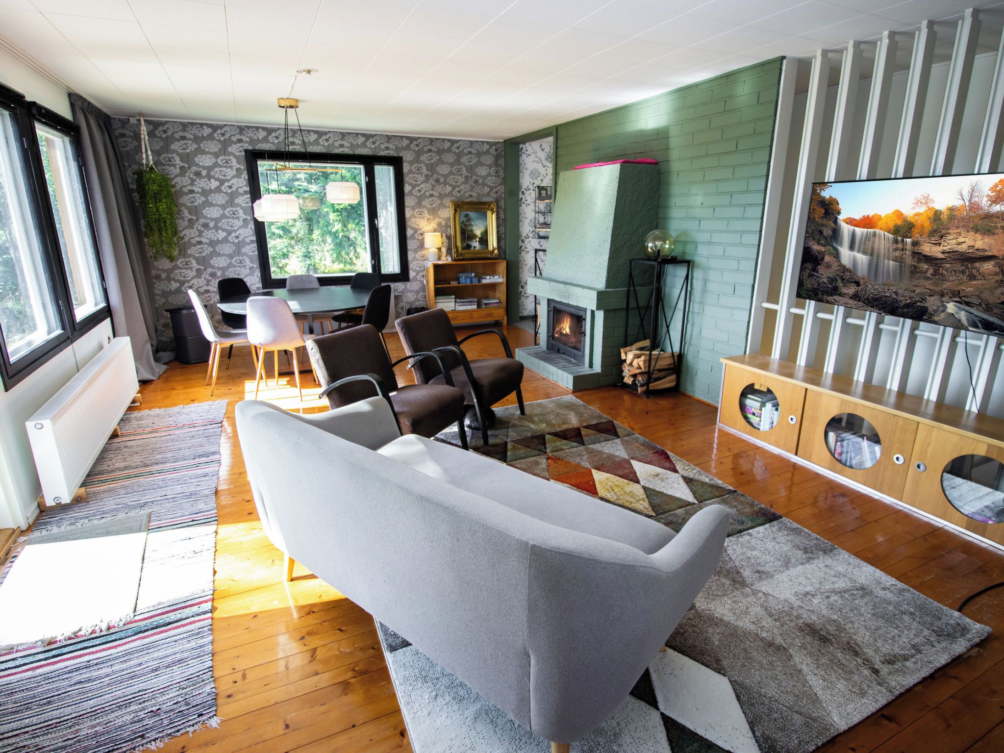 Een moderne woonkamer met een open haard, een televisie en een eethoek.