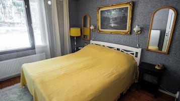 Une chambre à coucher avec un lit, une fenêtre, un tableau et un miroir.