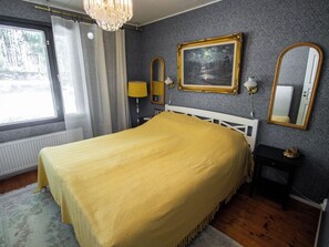Ein Schlafzimmer mit Bett, Fenster, einem Gemälde und einem Spiegel.