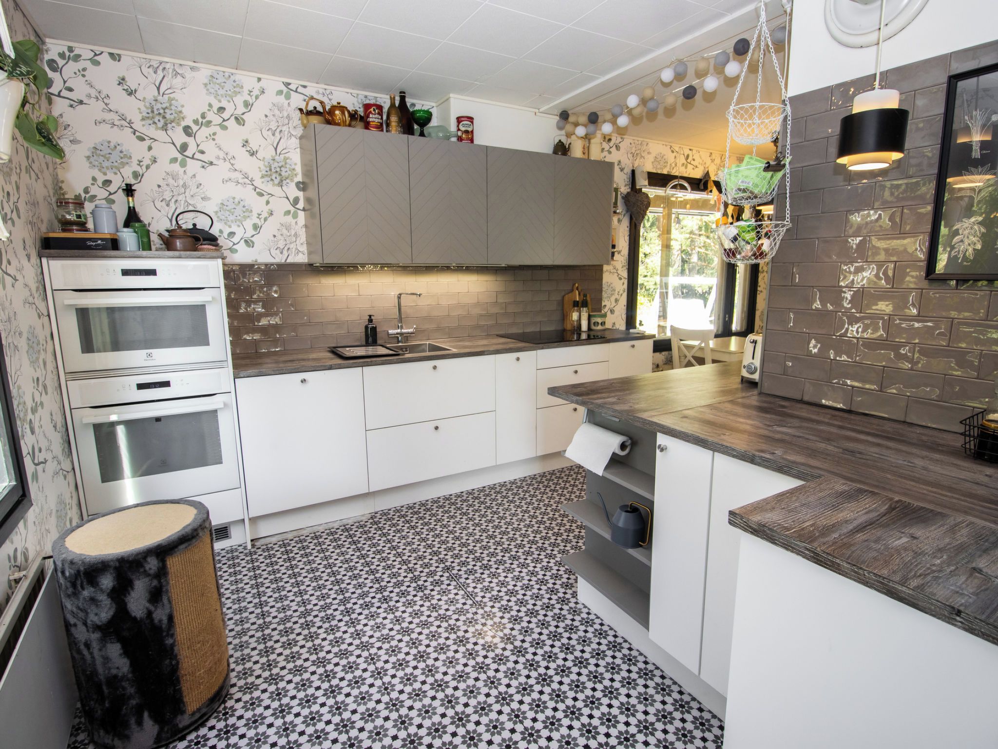 Une cuisine moderne avec des meubles blancs, un four encastré, un évier et un sol à motifs.