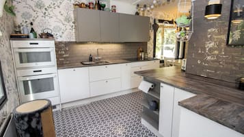 Une cuisine moderne avec des meubles blancs, un four encastré, un évier et un sol à motifs.