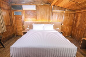 A wooden cabin room with a bed, nightstands, and an air conditioning unit. - Sajiwa Villa Bandungan (Jawa Tengah)