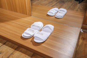 A wooden bench with a pair of white slippers placed on it.
