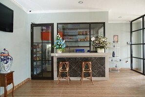 A kitchen area with a marble countertop, two stools, a refrigerator, and a shelf with decorative items. - TAKE Guesthouse 2 (Jambi)