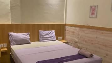 Une chambre avec un lit simple, une tête de lit en bois, une table de chevet et un luminaire fixé au mur.