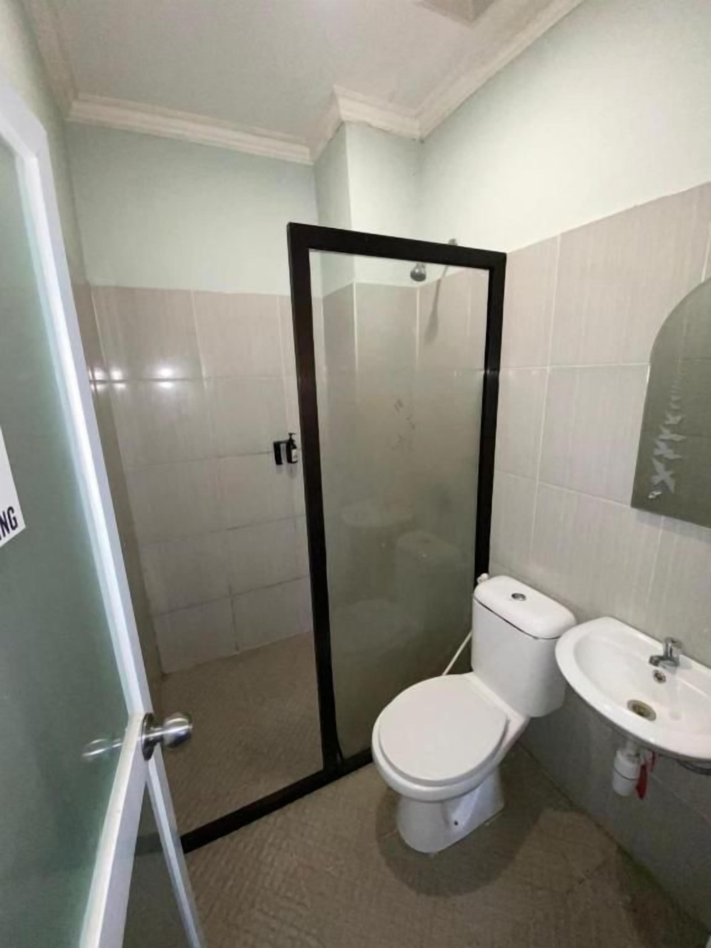 A bathroom with a glass-enclosed shower, a toilet, and a sink.