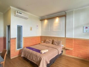 Een hotelkamer met een bed, een bureau en een airconditioning.