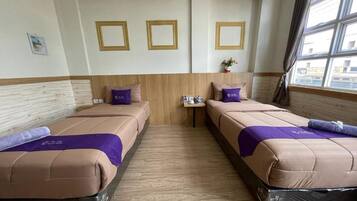 A hotel room with two beds, a small table, and a window with curtains.