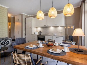 A modern kitchen with white cabinets, a dining table with placemats, and a coffee machine. - 8, Residence Dunenstrasse (Binz)