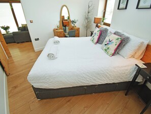 A neatly made bed with rolled towels, a bedside table with a lamp, and a mirror on the wall. - 1 bedroom accommodation in Carr Bank, Arnside (Carr Bank, Arnside)