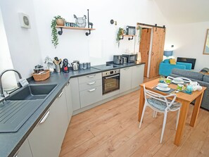 Une cuisine moderne dotée d’un four encastré, une table à manger avec des chaises et un coin salon comprenant un canapé et une table basse.
