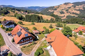 Ein ländliches Dorf mit traditionellen Häusern, einer Straße und umliegenden Hügeln.