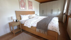 Ein Schlafzimmer mit einem hölzernen Bett, einem Nachttisch mit Lampe und einem großen Kleiderschrank.
