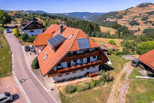 Eine traditionelle Chalet mit geneigtem Dach, Solaranlagen und einem malerischen Bergpanorama.