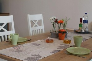 Ein Esstisch ist gedeckt mit Tellern, Besteck und einer Blumenvase.