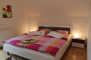 Ein Schlafzimmer mit einem Bett, Nachttischen, einem Wandbild und einer Ablagefläche.