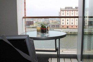 Ein Balkon mit einem Glastisch, zwei Weingläsern und einer Weinflasche.