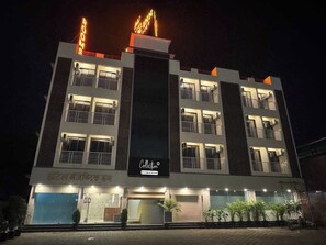 Un hotel de varios pisos con un letrero grande que dice 'Rooms', un letrero que dice 'Collection' y una entrada visible con un área techada.