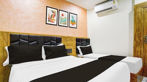 Habitación de hotel con dos camas, cabecera de madera, piso de mármol y aire acondicionado.