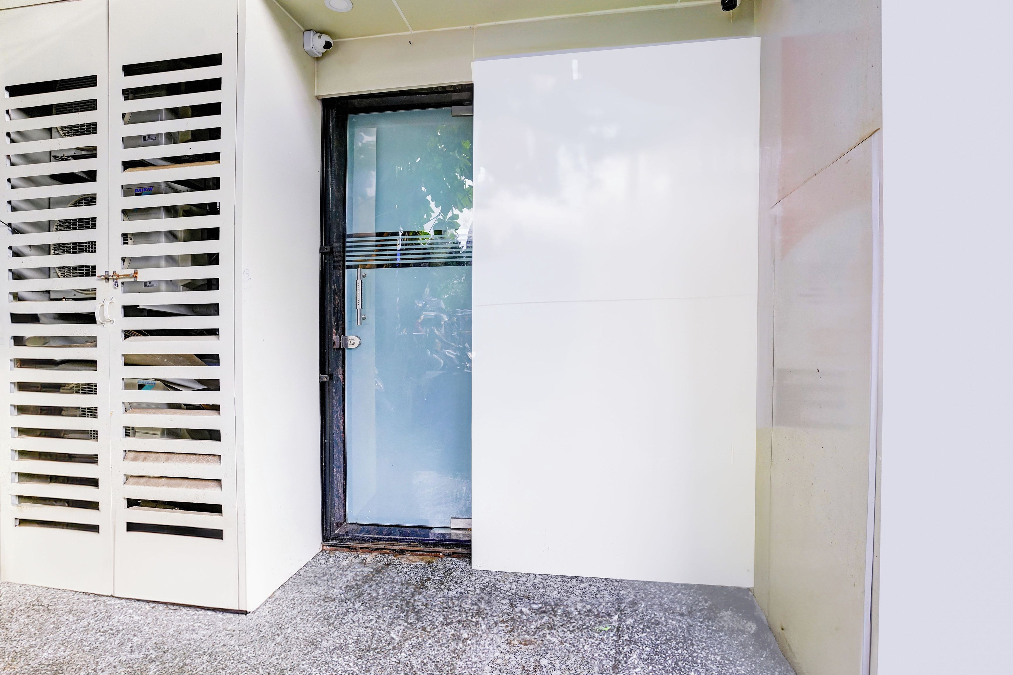 A door with a glass panel, a metal handle, and a security camera above it.