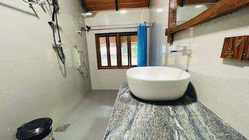 A bathroom with a white sink, a shower, and a window with a view.