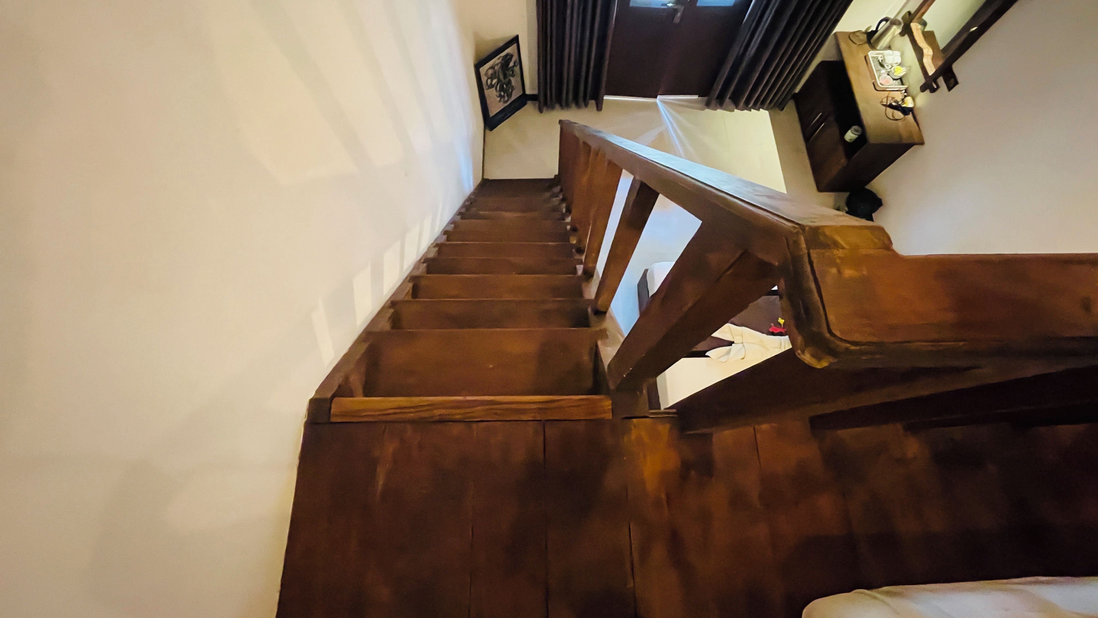 A wooden staircase with a handrail leading to a landing.